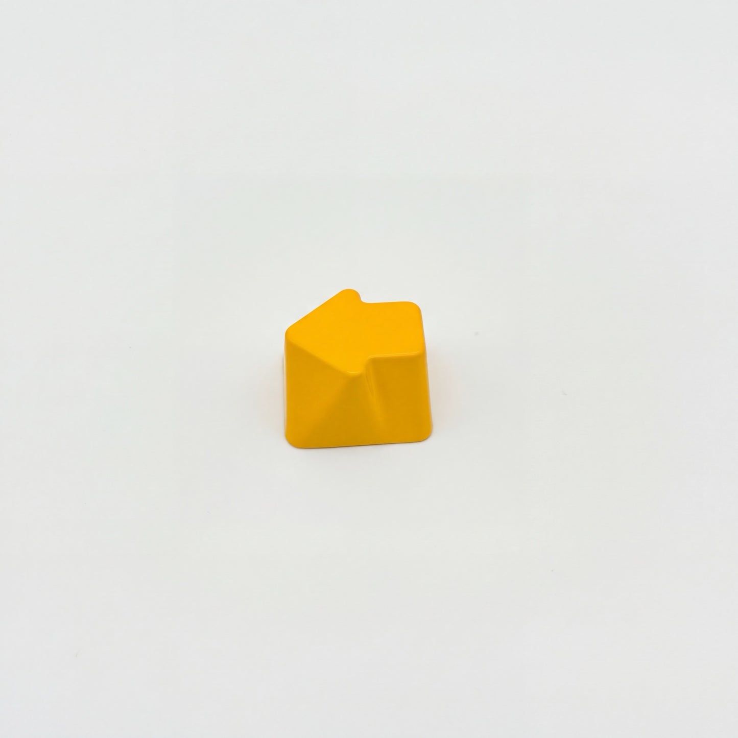 Sculpted arrow custom keycap golden yellow die-cast metal smooth lacquer top view on white background